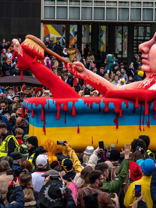Ein Karnevalswagen zeigt Russlands Präsidenten Putin in einer Badewanne voller Blut. Die Badewanne ist blau und gelb, wie die Farben der Ukraine-Flagge.