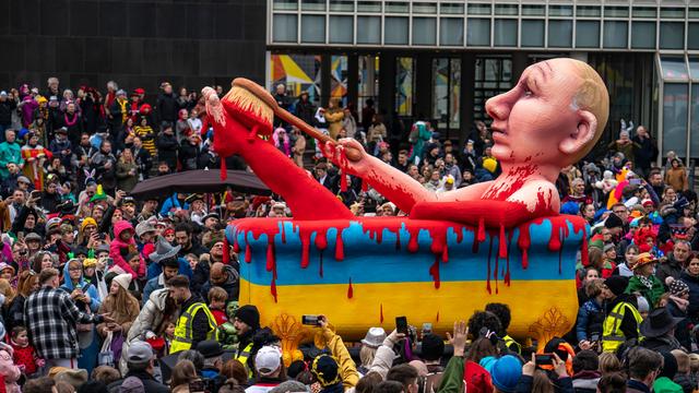 Der Karnevals-Wagen von Jacques Tilly zeigt den russischen Präsidenten Putin in einer gelb-blauen Badewanne. Putin badet in Blut. Der Wagen zieht durch eine große Menschen-Menge in der Stadt Düsseldorf.