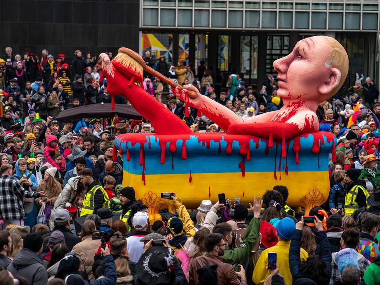 Ein Karnevalswagen zeigt Russlands Präsidenten Putin in einer Badewanne voller Blut. Die Badewanne ist blau und gelb, wie die Farben der Ukraine-Flagge.
