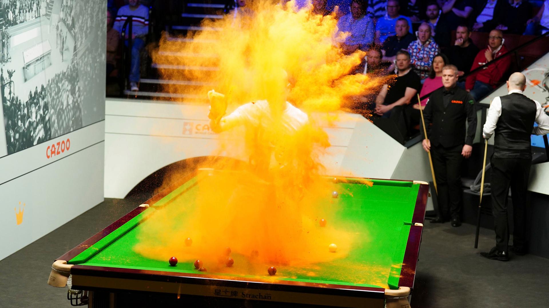 Ein Mann ist auf einem Billard-Tisch gesprungen und verteilt orange-farbenes Pulver. Ein Mann ist auf einem Billard-Tisch gesprungen und verteilt orange-farbenes Pulver.