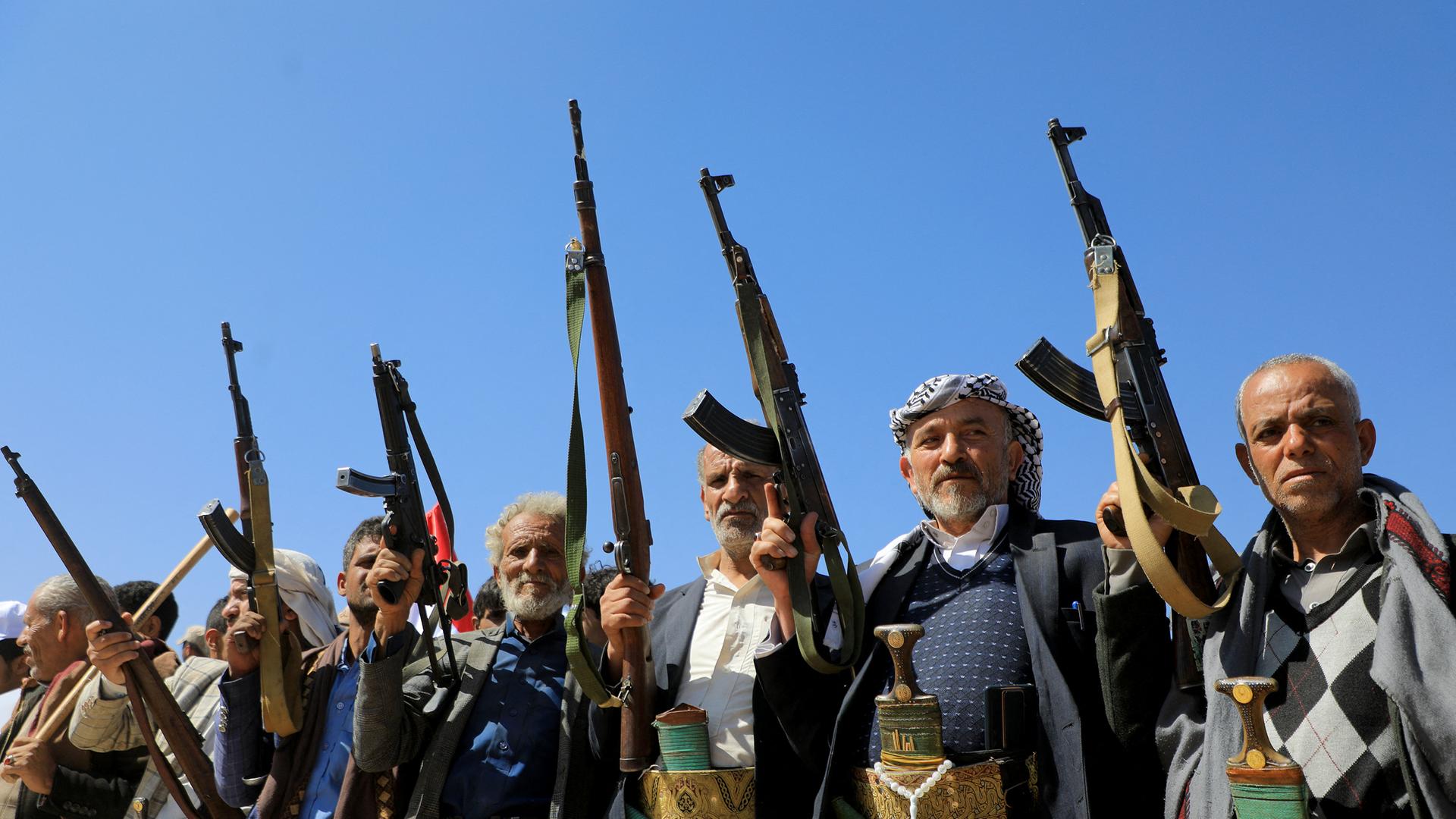 Demonstrierende Huthi-Unterstützer recken ihre Waffen in den Himmel.