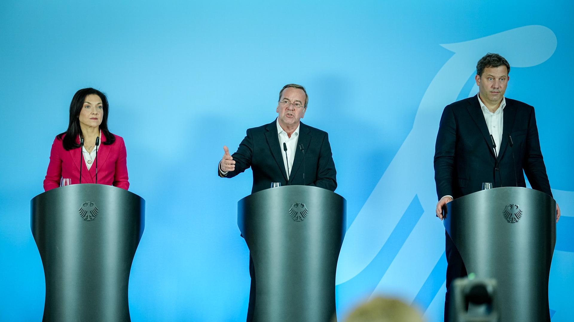 Bundeswirtschaftsministerin Katherina Reiche, Bundesverteidigungsminister Pistorius und Bundeswirtschaftsminister Klingbeil geben gemeinsam eine Pressekonferenz. Sie stehen hinter silbernen Stehpulten. Pistorius redet. 