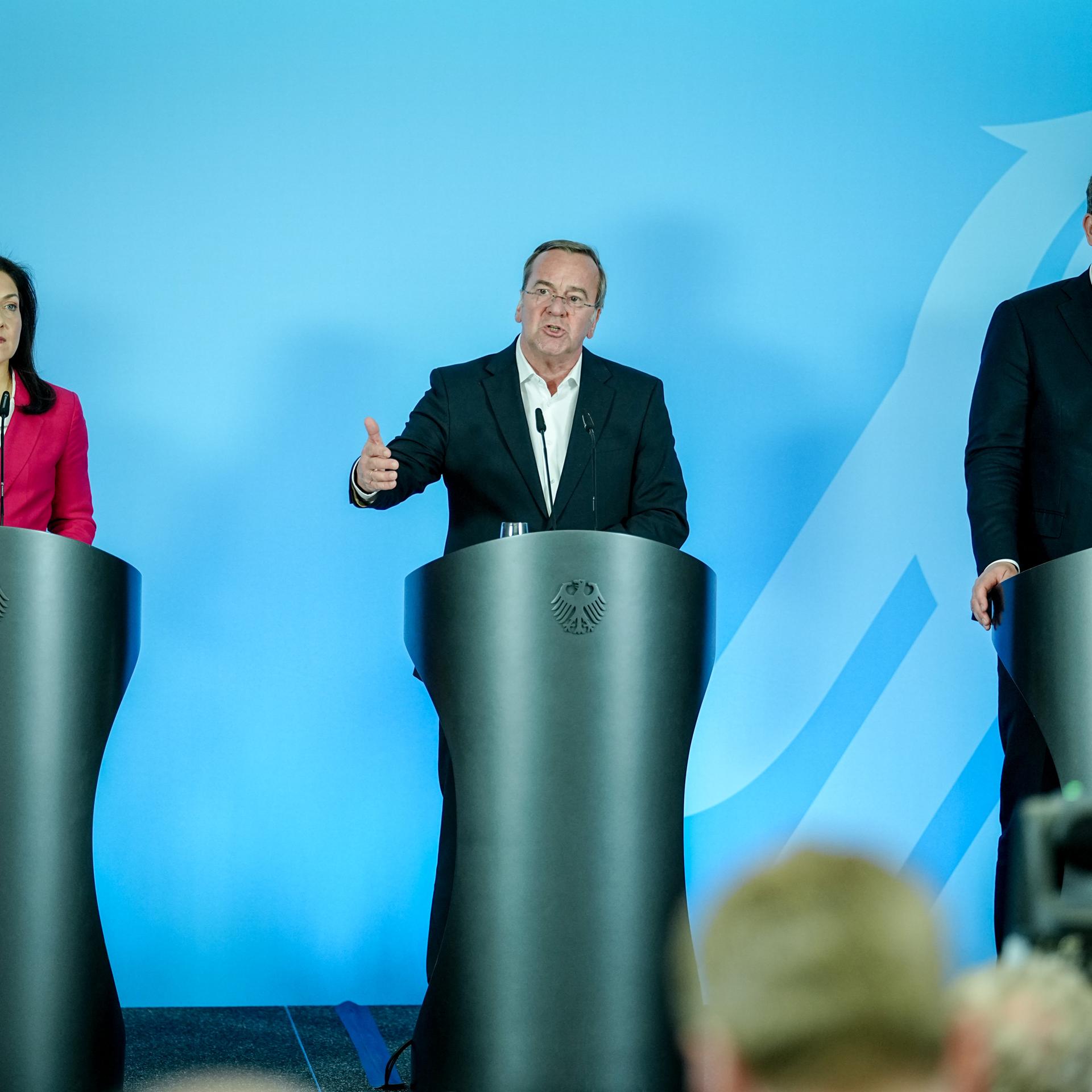 Bundeswirtschaftsministerin Katherina Reiche, Bundesverteidigungsminister Pistorius und Bundeswirtschaftsminister Klingbeil geben gemeinsam eine Pressekonferenz. Sie stehen hinter silbernen Stehpulten. Pistorius redet. 