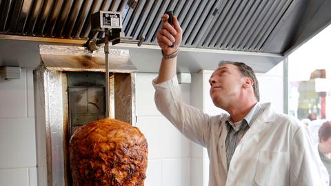 Ein Kotrolleur überprüft eine Dunstabzugshaube über einem Dönerspieß