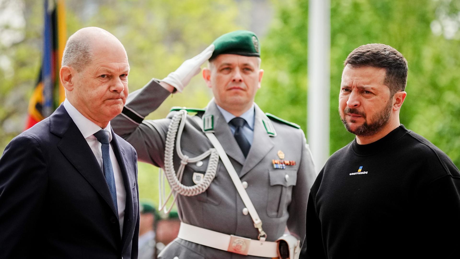 Bundeskanzler Olaf Scholz und Wolodymyr Selenskyj, Präsident der Ukraine beim Fahnenappell mit einem Bundeswehrsoldaten