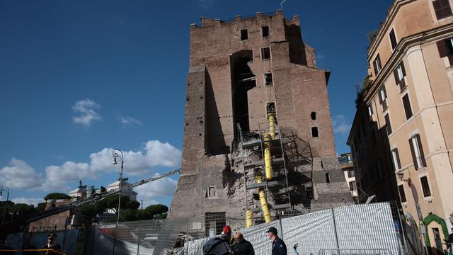 Das Foto zeigt den Turm mit zum Teil eingestürzter Seitenwand. Davor stehen Geräte und Helfer von der Feuerwehr.