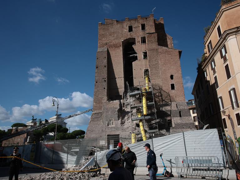 Der mittelalterliche Torre Dei Conti mit zum Teil eingestürzter Seitenwand. Davor stehen Geräte und Helfer der Feuerwehr.