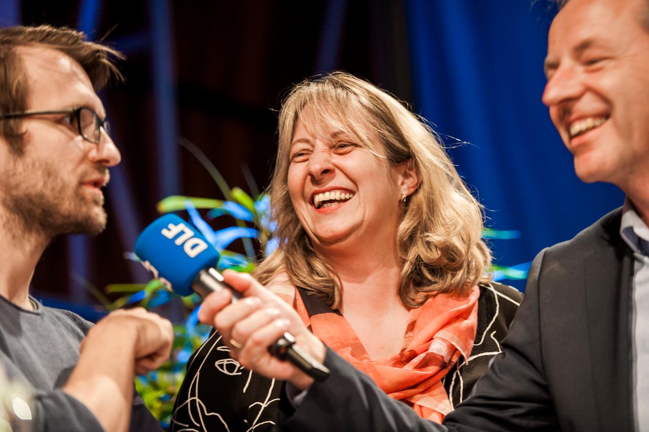 Drei Menschen sprechen bei einer Veranstaltung in Köln im Jahr 2015 mit einem Mikrofon.
