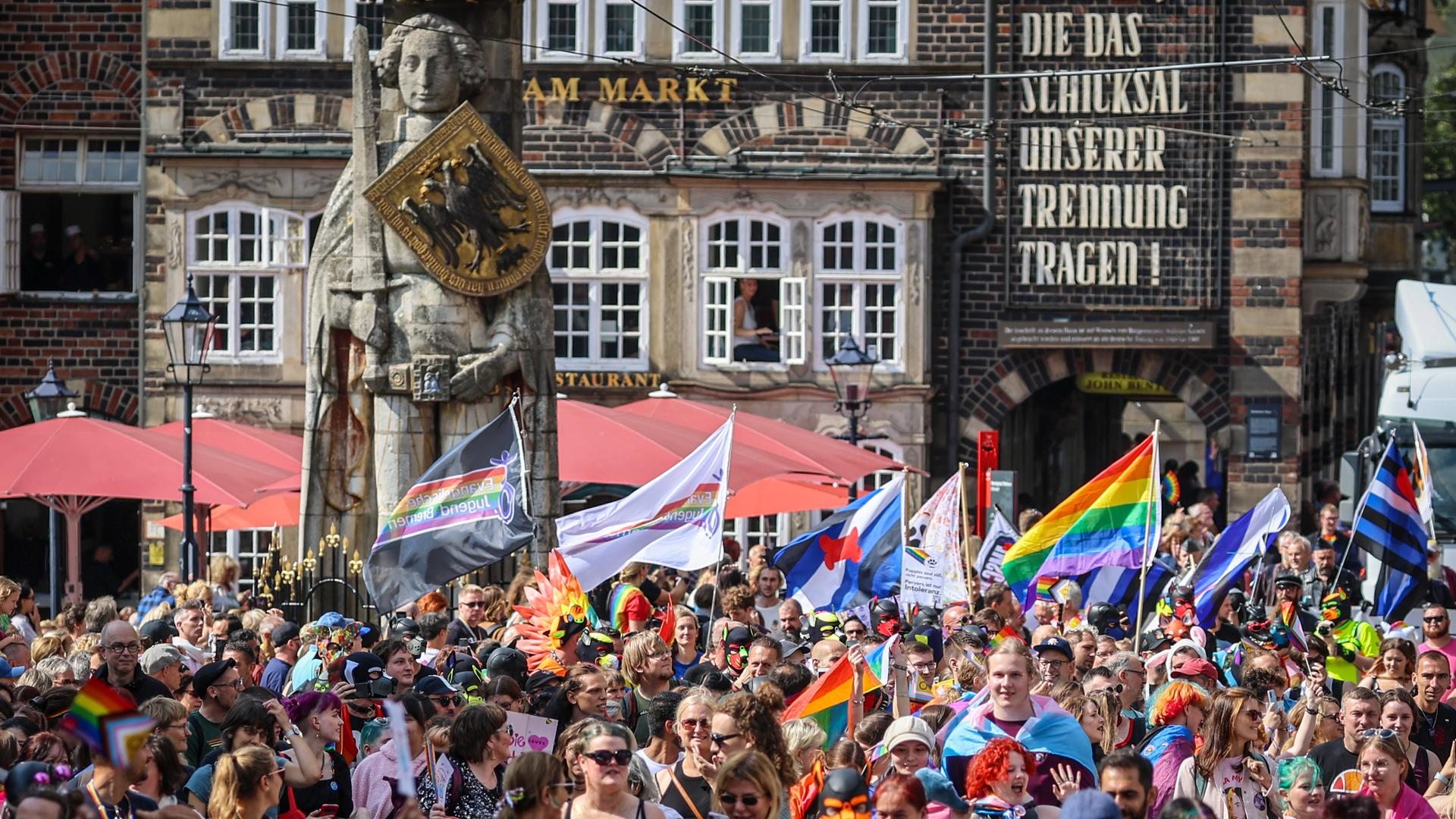 Teilnehmer des Christopher Street Days (CSD) gehen mit Fahnen und Transparenten über den Marktplatz am Roland vorbei. Teilnehmer des Christopher Street Days (CSD) gehen mit Fahnen und Transparenten über den Marktplatz am Roland vorbei.