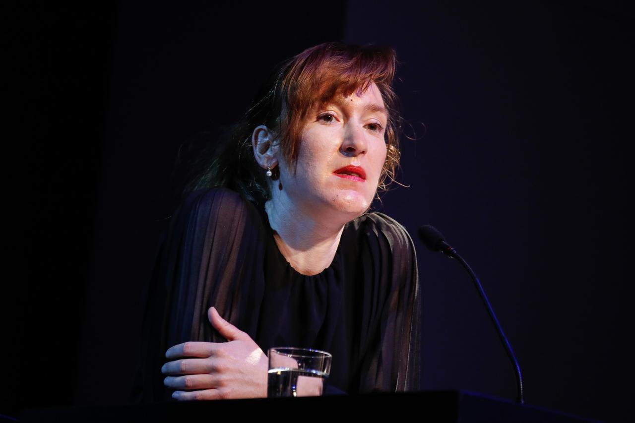 Die Autorin Nora Bossong sitzt in nachdenklicher Pose auf einem Podium.