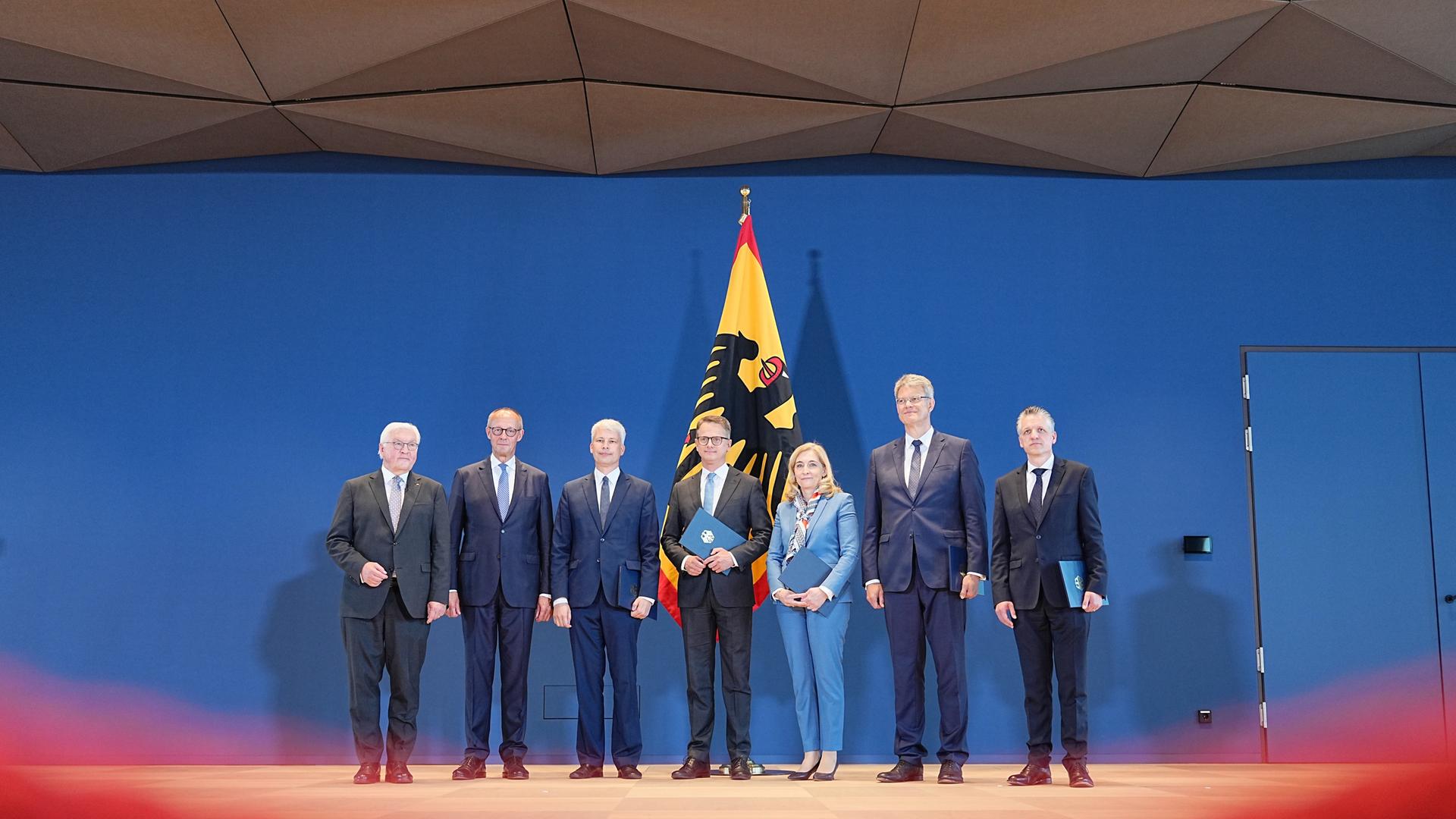 Politiker stehen zusammen vor einer Flagge mit Bundesadler.