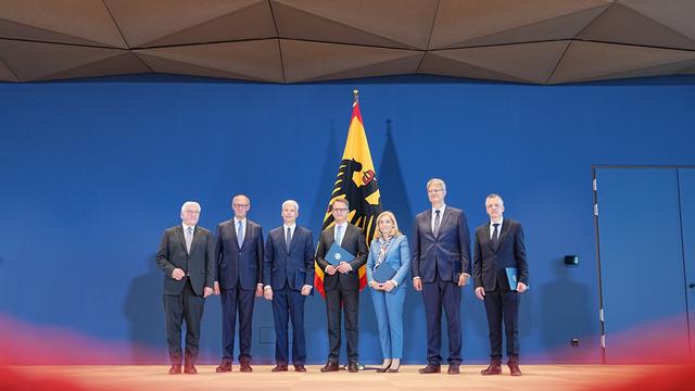 Politiker stehen zusammen vor einer Flagge mit Bundesadler.