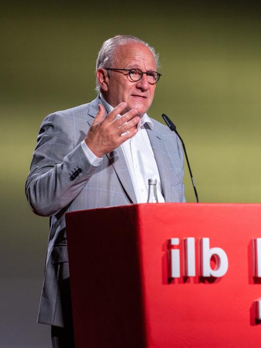 Ulrich Schreiber steht an einem roten Rednerpult mit der Aufschrift "ilb"