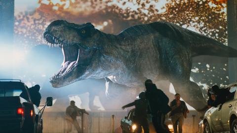 Filmszene aus "Jurassic World 3", ein T-Rex Dinosaurier setzt die Menschen in einem Autokino in Angst und Schrecken.