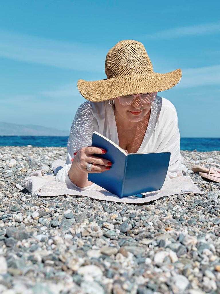 Eine Frau liest ein Buch an einem Strand