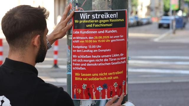 Ein Mann klebt ein Plakat für die Aktion an einen Laternen-Pfahl.