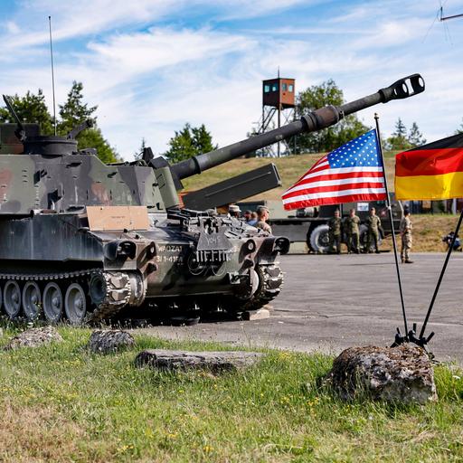 Ein US-amerikanischer Paladin-Panzer steht hinter zwei Fahnen der USA und Deutschland bei einer multinationalen Artillerie-Feuerübung der US-Armee mit knapp 2400 Soldaten aus 19 Nationen auf dem Truppenübungsplatz Grafenwöhr in Bayern.