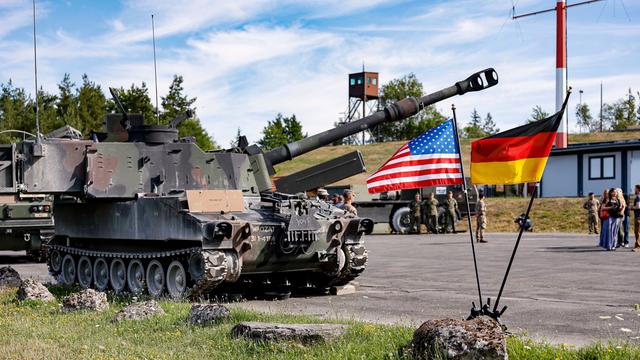 Ein US-amerikanischer Paladin-Panzer steht hinter zwei Fahnen der USA und Deutschland auf US-Stützpunkt Grafenwöhr in Bayern.