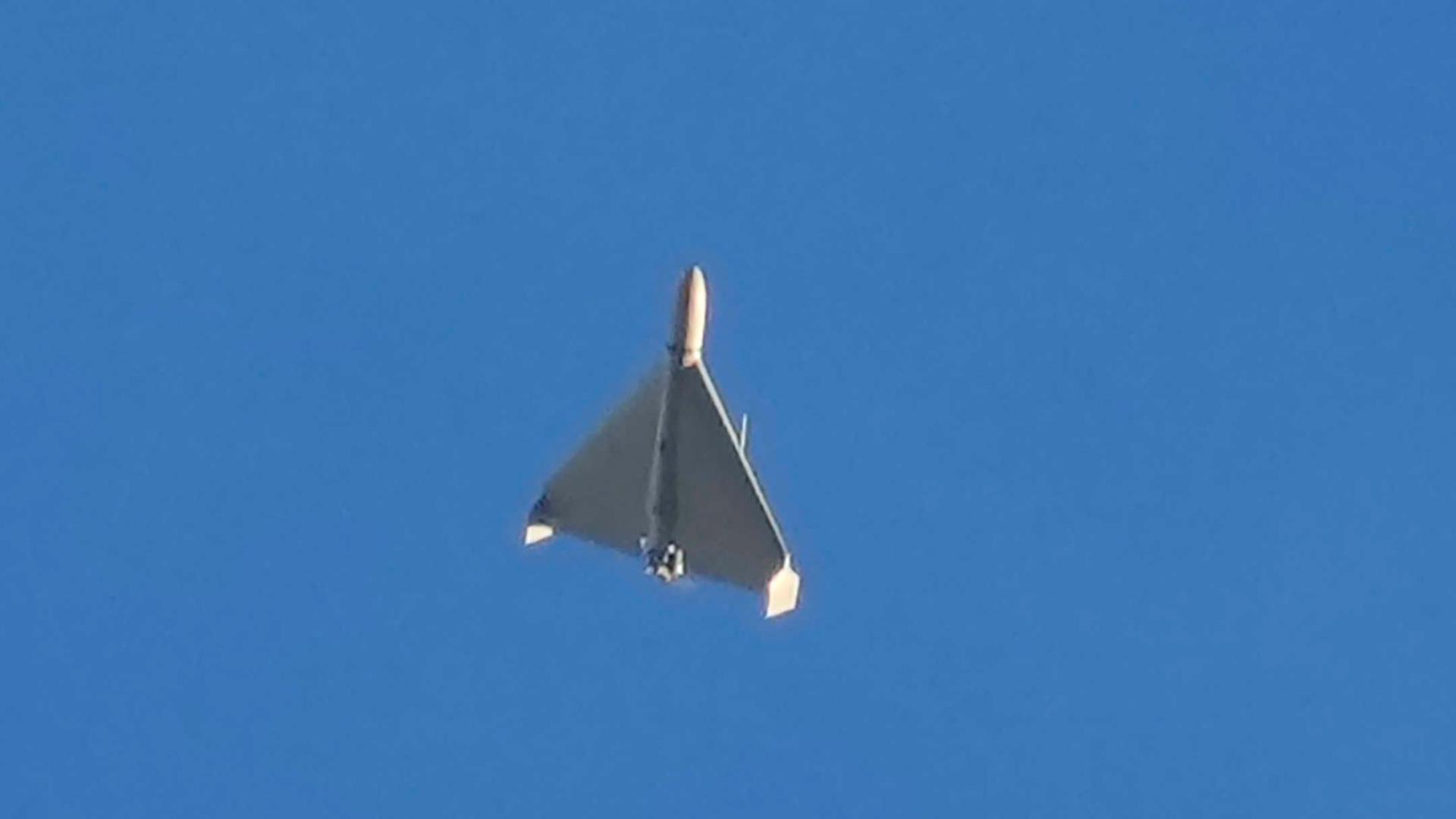 Das Bild zeigt eine Drohne von unten gesehen bei ihrem Flug unter einem blauen Himmel. 