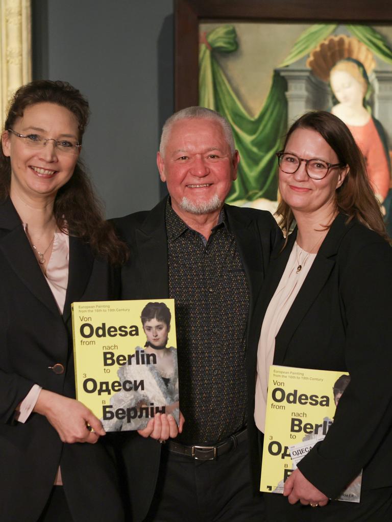 Zwei Frauen und ein Mann in ihrer Mitte präsentieren den Ausstellungskatalog der Schau "Von Odsea nach Berlin. Europäische Malerei des 16. bis 19. Jahrhunderts"). Im Hintergrund sind Bilder in den Ausstellungsräumen zu sehen. 