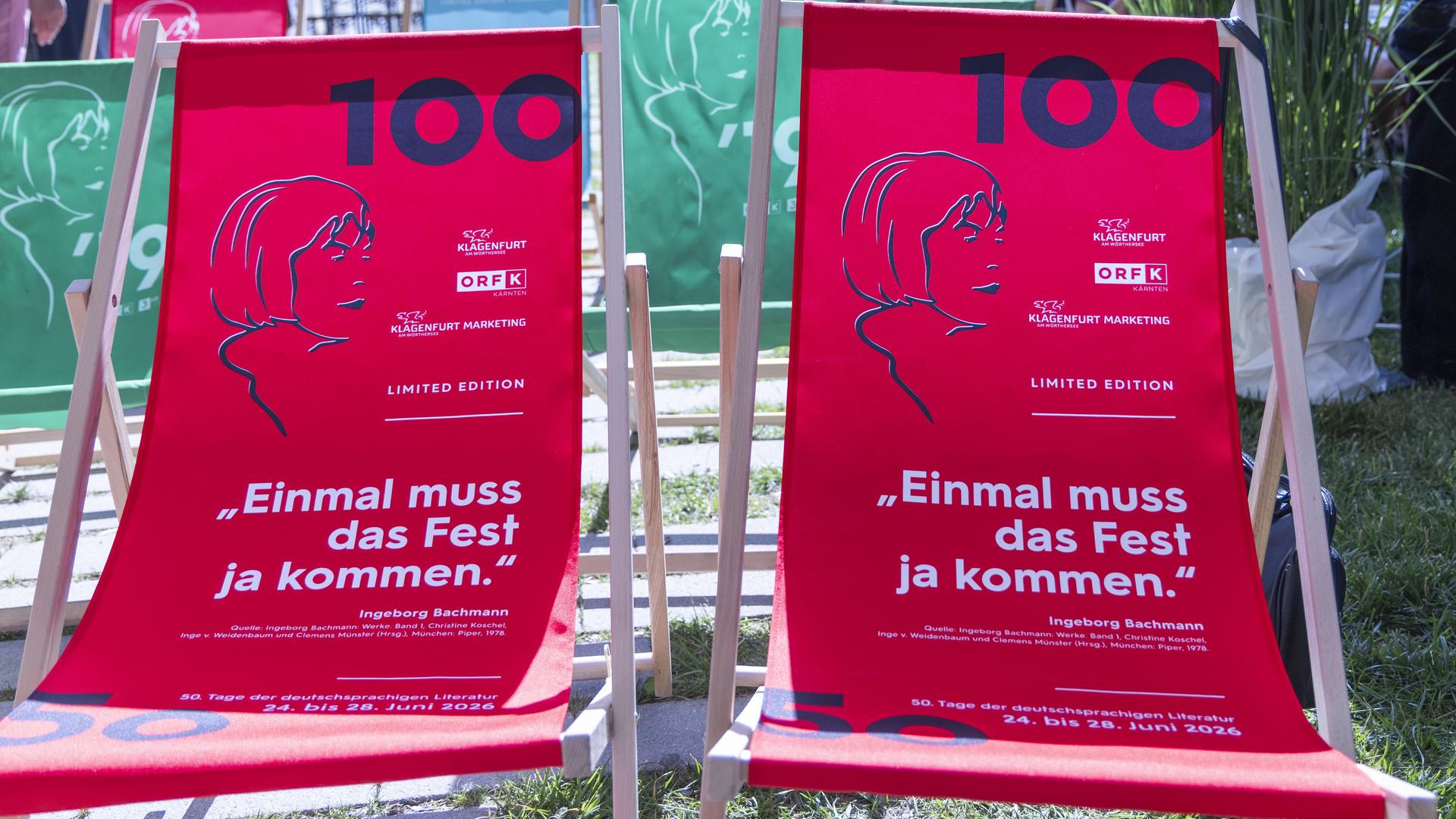 Zwei rote Strandliegen mit dem Konterfei der Schriftstellerin Ingeborg Bachmann und der Ziffer 100 auf dem Stoff stehen in einem Garten.