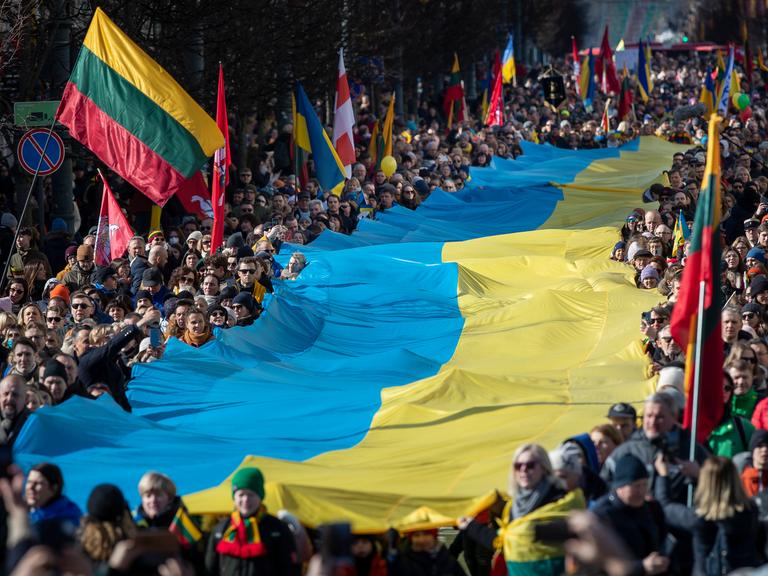 Menschen tragen am 11.03.2022 eine riesige Ukrainische Flagge bei den Feierlichkeiten zu Litauens 1991 erlangter Unabhängigkeit in der Hauptstadt Vilnius