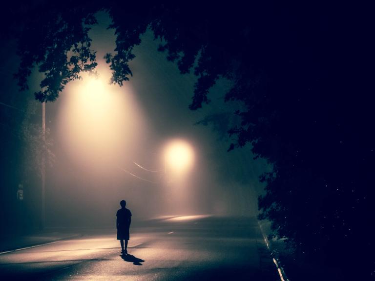 Eine Person ist allein nachts auf der Straße unterwegs.