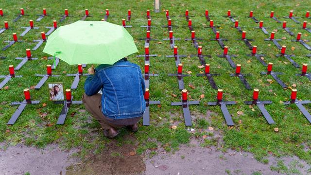 Ein Mann kniet neben 135 Kreuzen. Sie wurden zur Erinnerung an die Opfer der Flut-Katastrophe im Ahr-Tal aufgestellt.