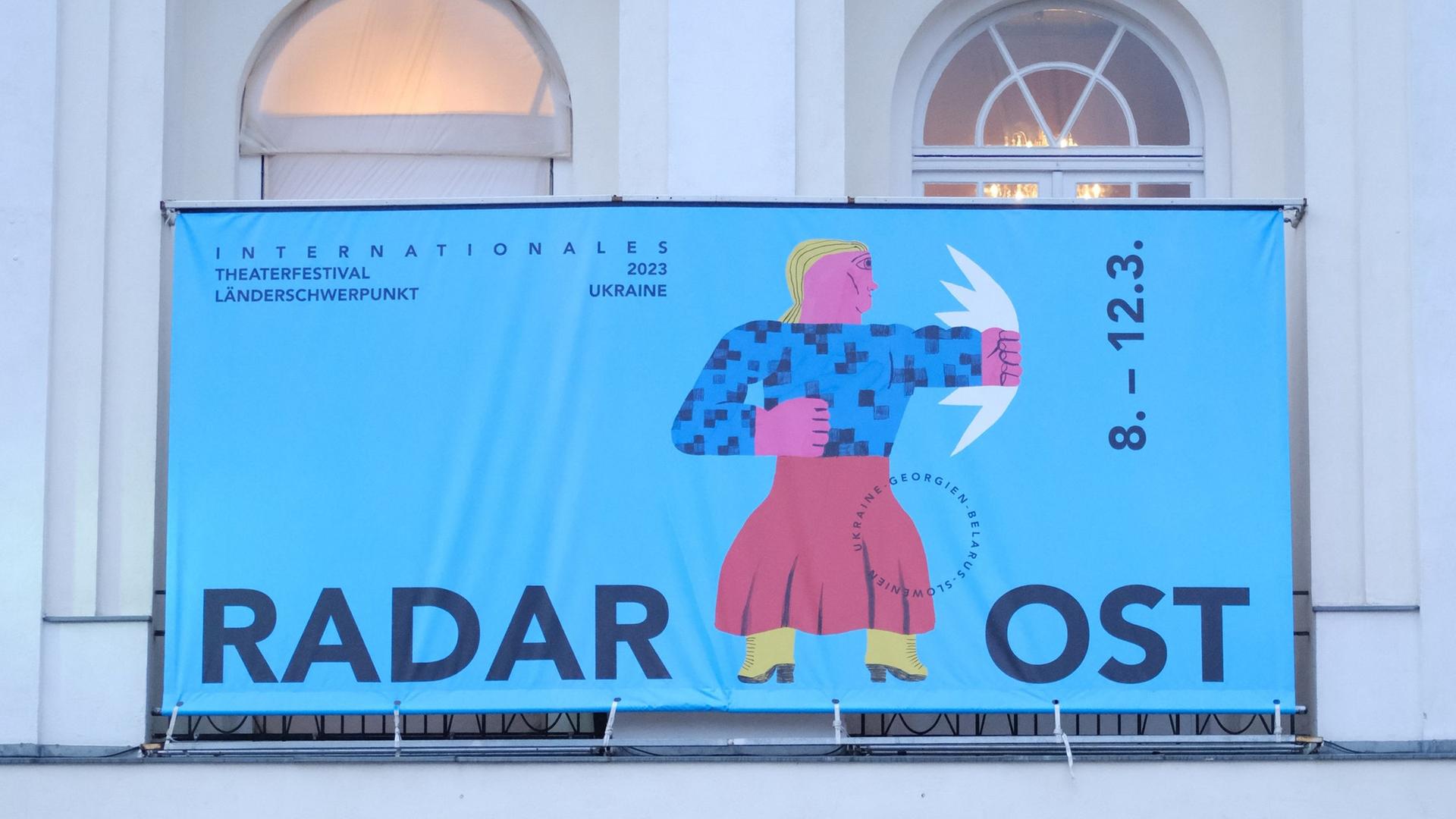 Über dem Eingang des deutsches Theaters hängt das Festivalplakat von "Radar Ost" mit einer Figur auf blauem Grund, die einen Faustschlag in Richtung Osten vollführt.