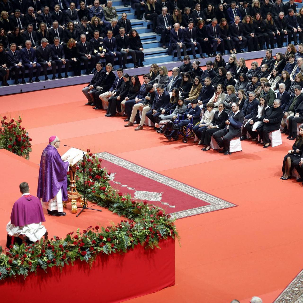 Viele Menschen sitzen in schwarzer Kleidung auf Bänken. Ein Pastor predigt auf einer Kanzel. Rechts sitzen der spanische König und seine Ehefrau.