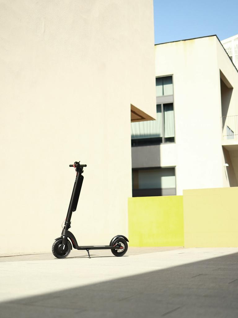 Ein schwarzer E-Scooter steht vor einer hellen Hauswand