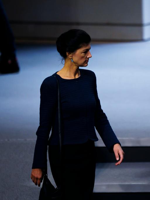 Sahra Wagenknecht geht im Plenarsaal des Deutschen Bundestags an den blauen Stuhlreihen vorbei.