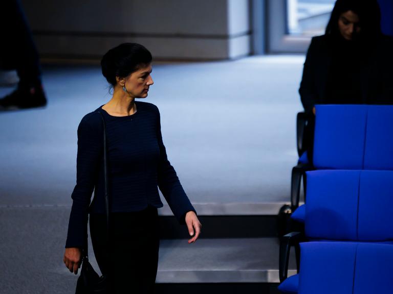 Sahra Wagenknecht geht im Plenarsaal des Deutschen Bundestags an den blauen Stuhlreihen vorbei.