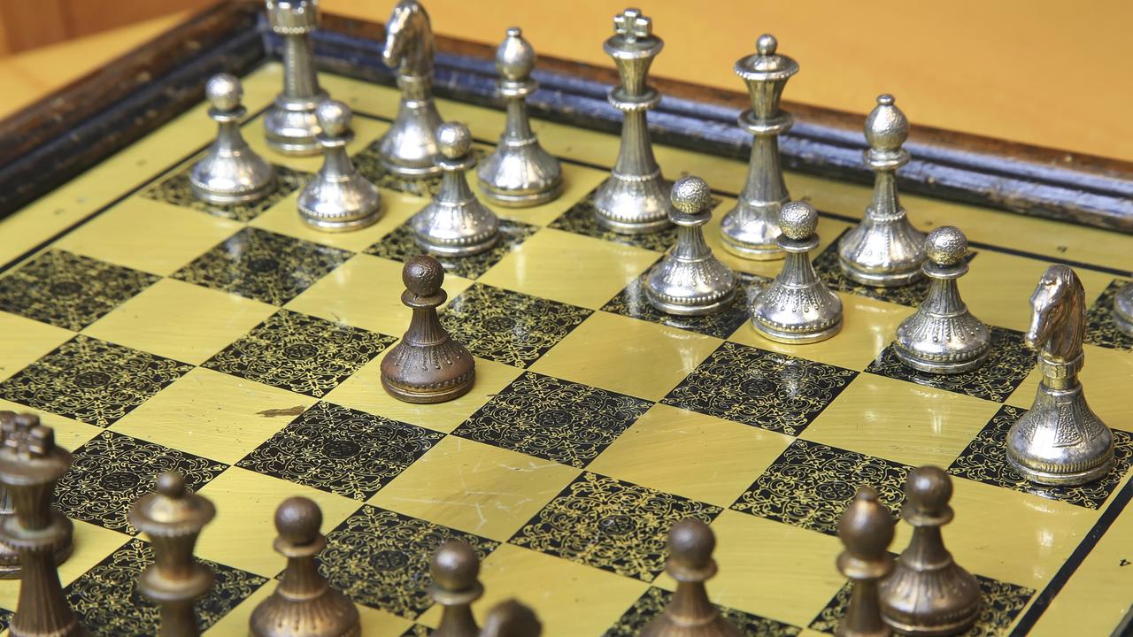 Ein edles Schachspiel auf einem gelb-schwarzen Brett mit metallischen Figuren in Silber und Bronze 