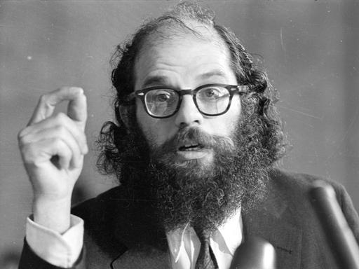 Allen Ginsberg deklamiert vor einem Mikrofon.