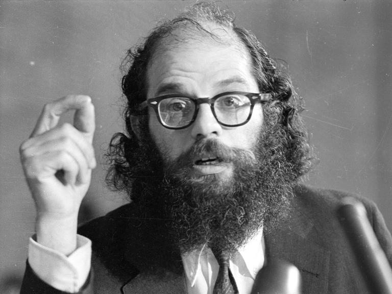 Allen Ginsberg deklamiert vor einem Mikrofon.