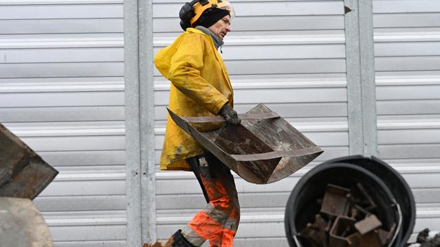 Ein Bau-Arbeiter trägt ein Stahl-Bauteil