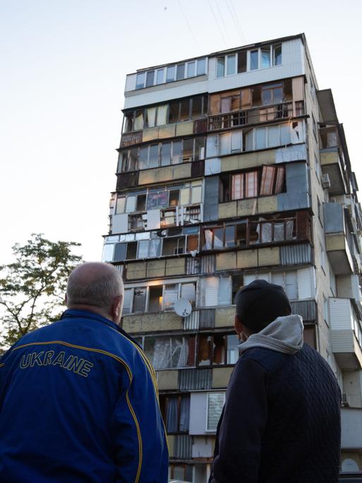 Zwei Männer stehen am Morgen nach den Luftangriffen vor einem zerstörten Haus.