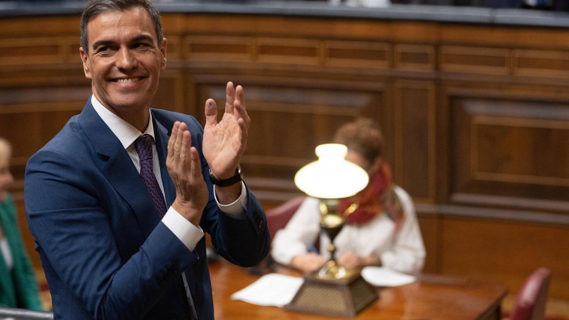 Pedro Sanchez im spanischen Parlament, er lächelt und klatscht in die Hände.