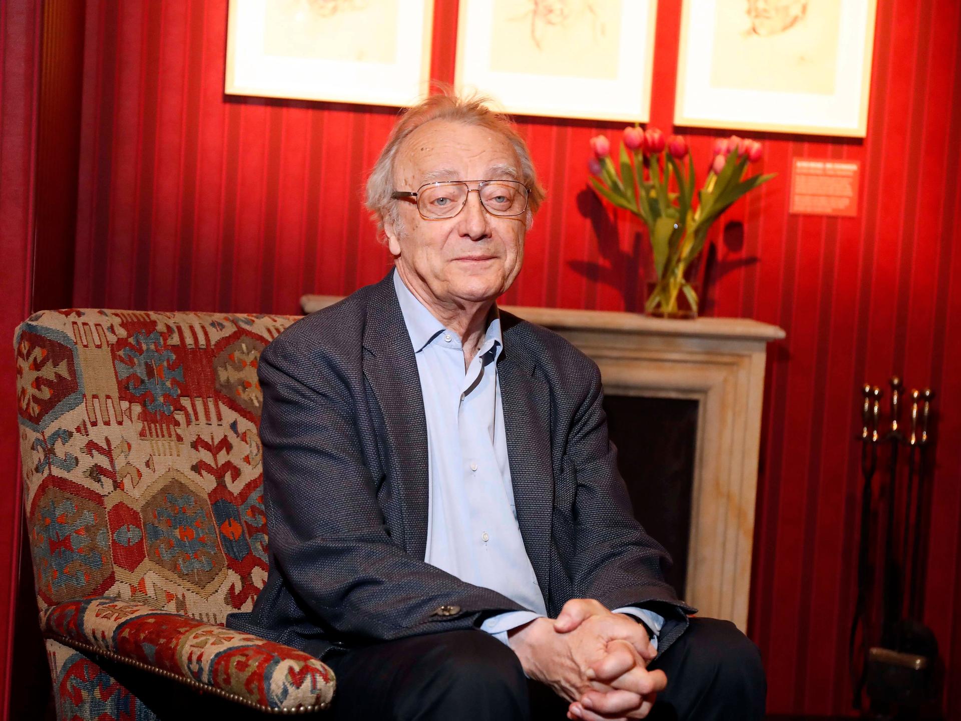 Der österreichische Pianist Alfred Brendel sitzt im April 2017 im Konzerthaus Berlin in einem Sessel vor einem Kamin, auf dessen Sims steht ein Strauß Tulpen. 