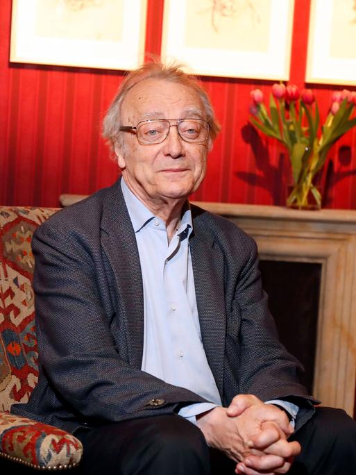Der österreichische Pianist Alfred Brendel sitzt im April 2017 im Konzerthaus Berlin in einem Sessel vor einem Kamin, auf dessen Sims steht ein Strauß Tulpen. 