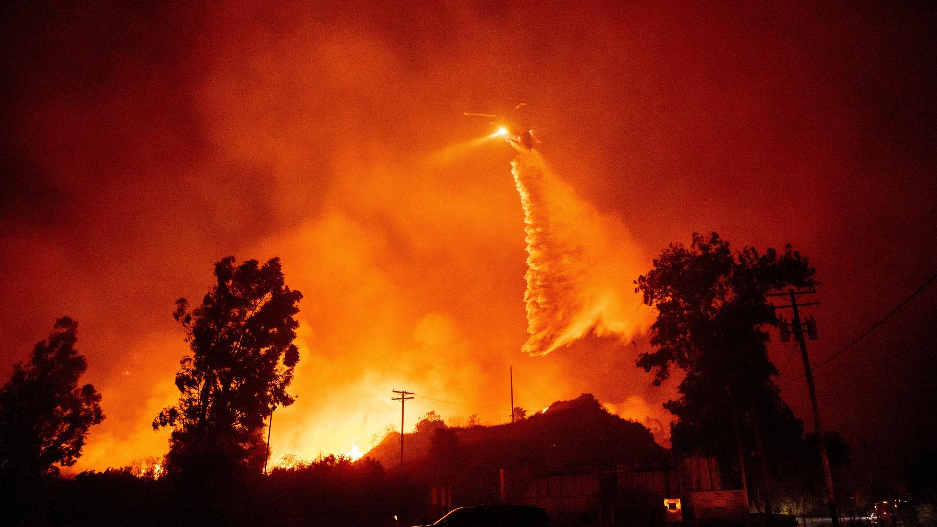 Ein Hubschrauber schüttet in der Nähe von Santa Paula, Kalifornien, Wasser auf die Flammen des Mountain Fire. Ein Hubschrauber schüttet in der Nähe von Santa Paula, Kalifornien, Wasser auf die Flammen des Mountain Fire.