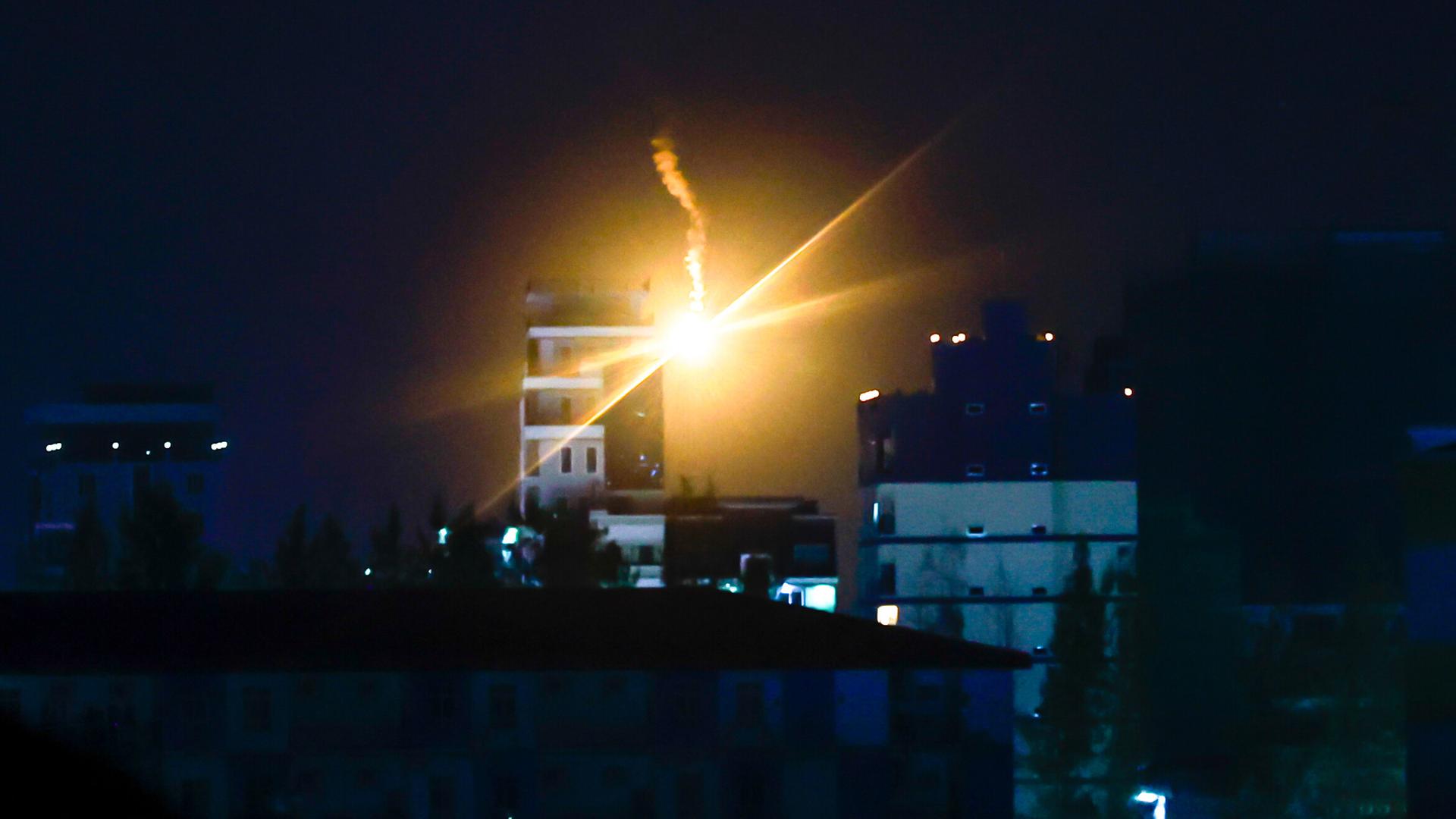 Eine Signalrakete erleuchtet den ansonsten dunklen Himmel über mehreren Häusern. 