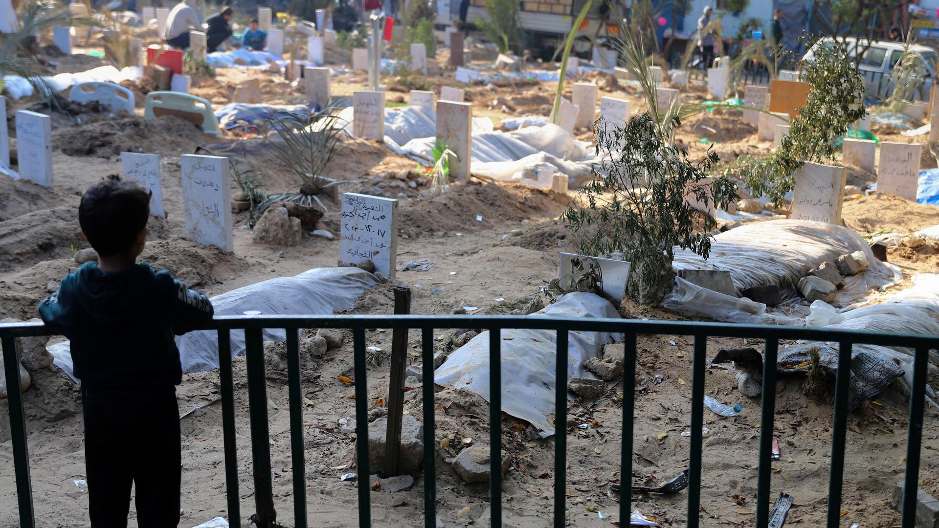 Ein palästinensisches Kind betrachtet die Gräber von Menschen, die bei der israelischen Bombardierung des Gazastreifens getötet und auf dem Gelände des Schifa-Krankenhauses in Gaza-Stadt begraben wurden.