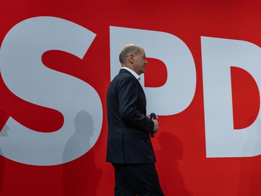 Bundeskanzler Olaf Scholz geht vor dem Logo seiner Partei, der SPD, von der Bühne