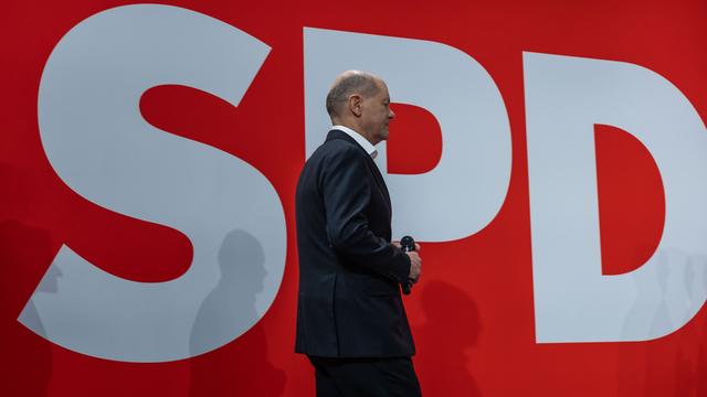 Bundeskanzler Olaf Scholz geht vor dem Logo seiner Partei, der SPD, von der Bühne