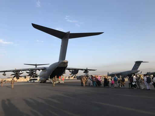 Menschen auf dem Rollfeld des Flughafens in Kabul drängen sich hinter einem Flugzeug der Bundeswehr
