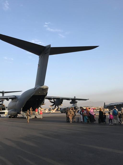 Menschen auf dem Rollfeld des Flughafens in Kabul drängen sich hinter einem Flugzeug der Bundeswehr