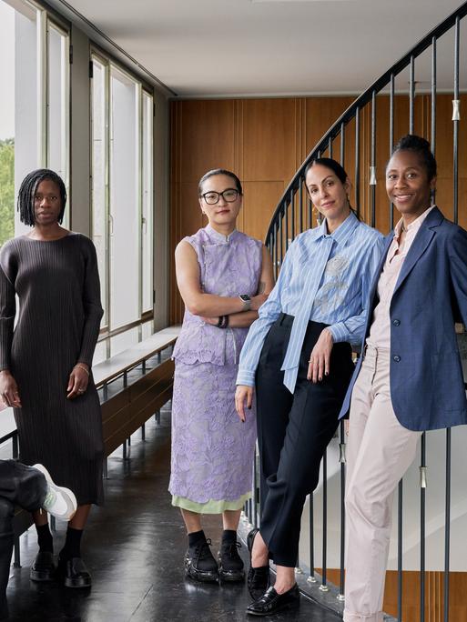 Das Künstlerische Team der documenta 16 steht in einem Treppenhaus. Alle lächeln in die Kamera.