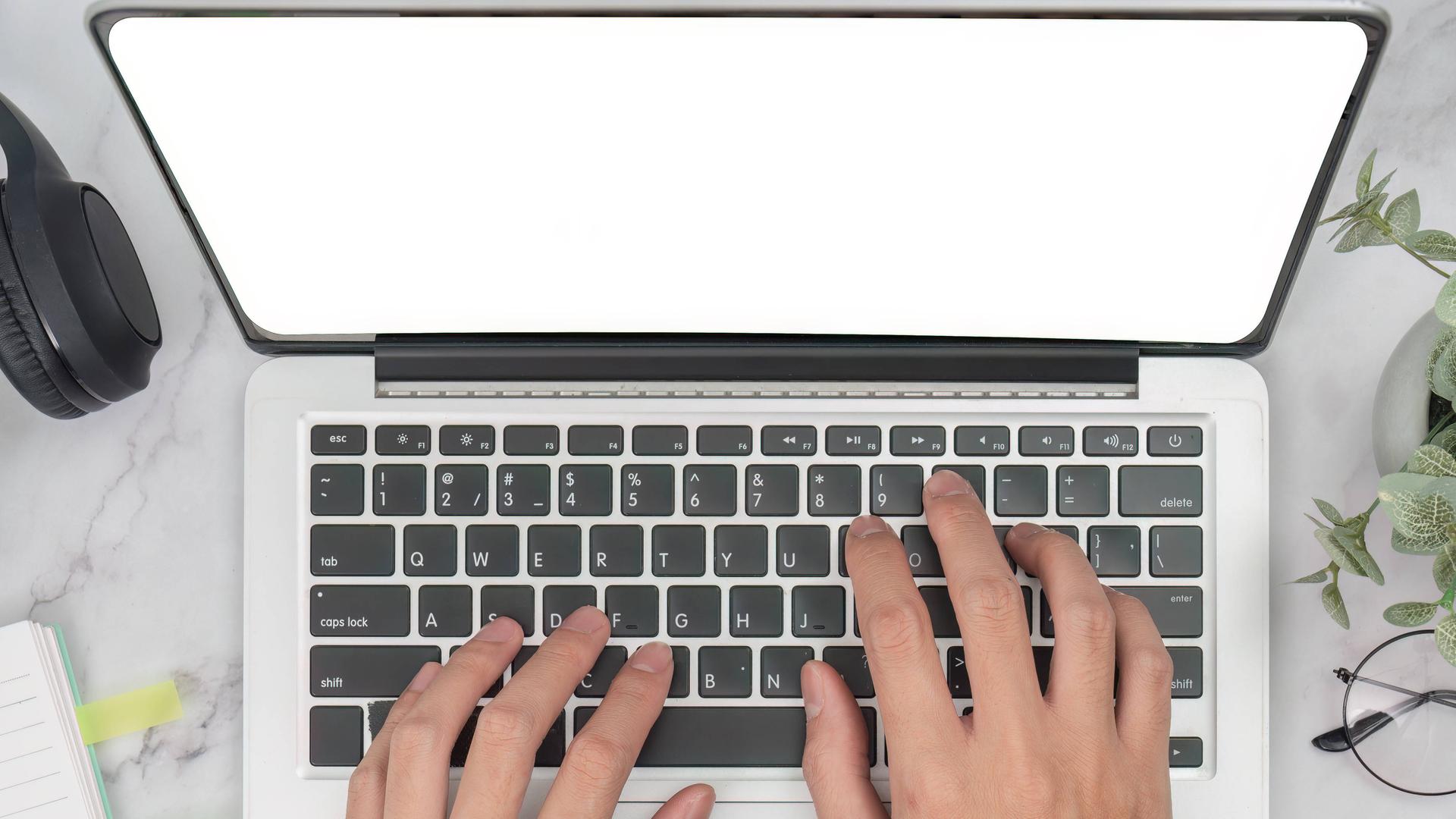 Hände tippen auf Laptop-Tastatur in modernem Arbeitsbereich mit Kaffee 
